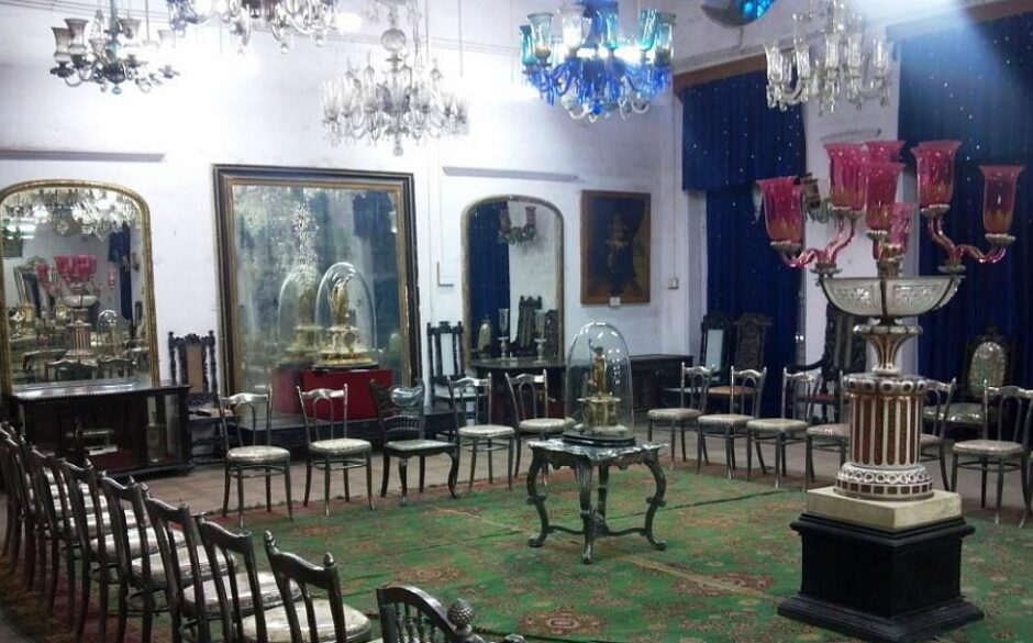 Interior of the Darbar Hall Museum, Gujarat. There is a large ornate green rug on the floor surrounded by period furniture.