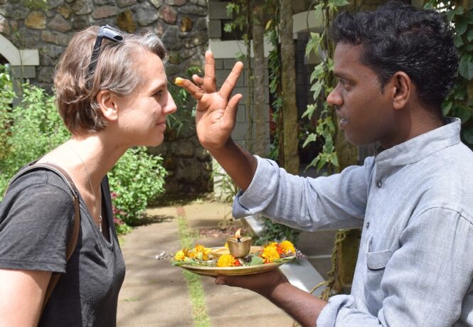 World Tourism Day 2024 - A customer being greeted at a hotel - the staff member dabbing her forehead with a traditional powder dot