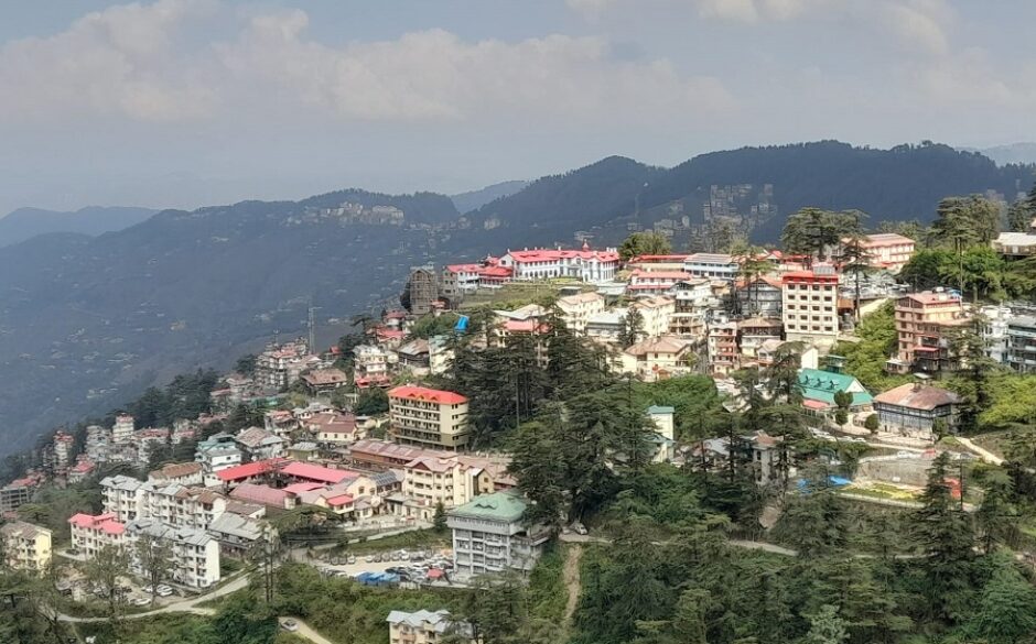 Beautiful view of Shimla, India. Colourful houses on the side of a hill with misty mountains in the background.