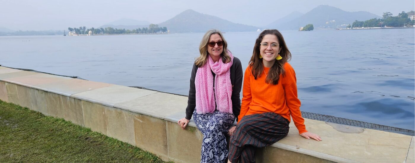 Photo of Jocelyn and other travelling companion in front of misty mountains and a large lake