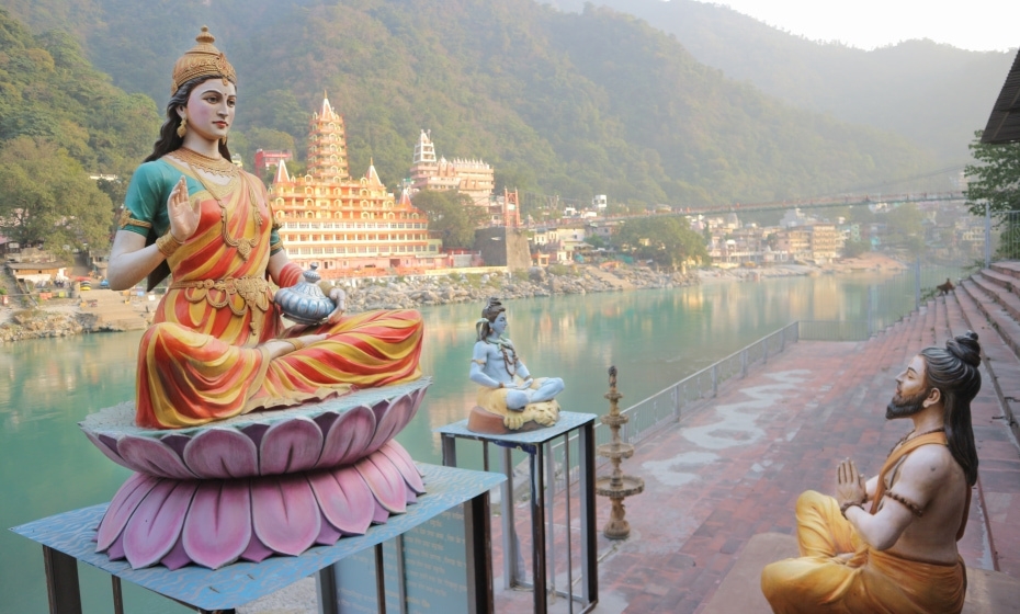 Spiritual Destinations in India - Sculptures of the Ganges, Shiva and the wise man on the river bank in Rishikesh
